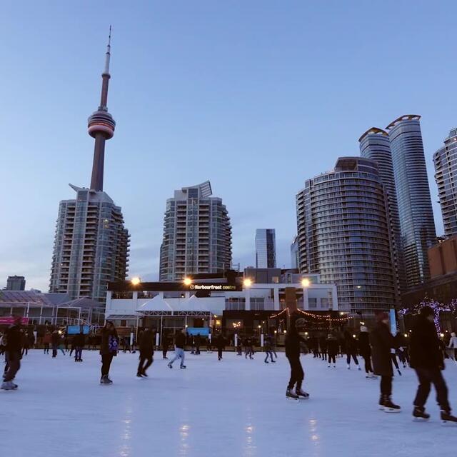 Skaters on an outdoor city ice rink at dusk